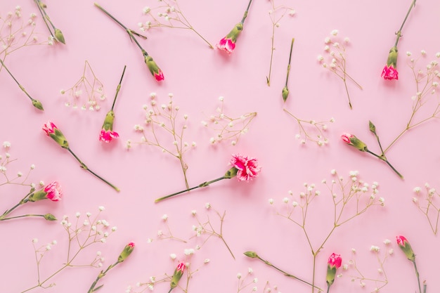 Flores cor de rosa com ramos de plantas na mesa