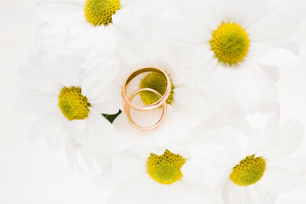 Foto grátis flores de alto ângulo com anéis de noivado