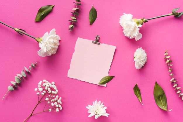 Flores de cravo com folha de papel em branco na mesa