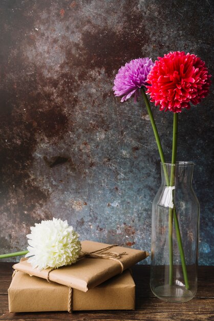 Flores de crisântemo colorido em vaso de vidro com caixas de presente embrulhado