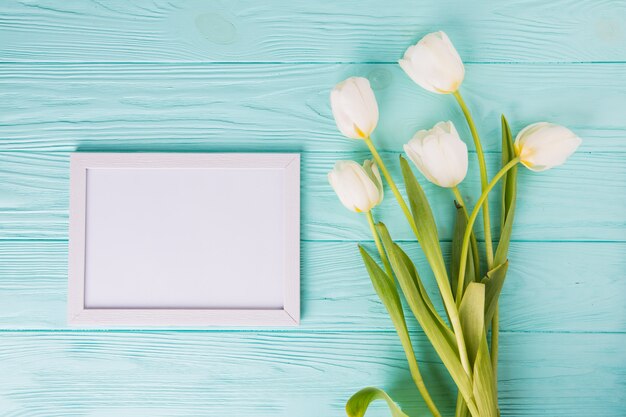 Flores de tulipa branca com moldura em branco na mesa