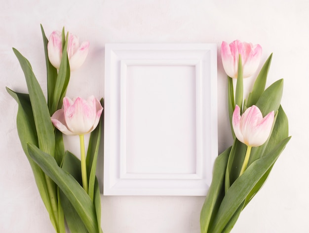 Flores de tulipa com moldura em branco na mesa