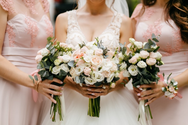 Flores do casamento, noiva e damas de honra segurando seus buquês no dia do casamento
