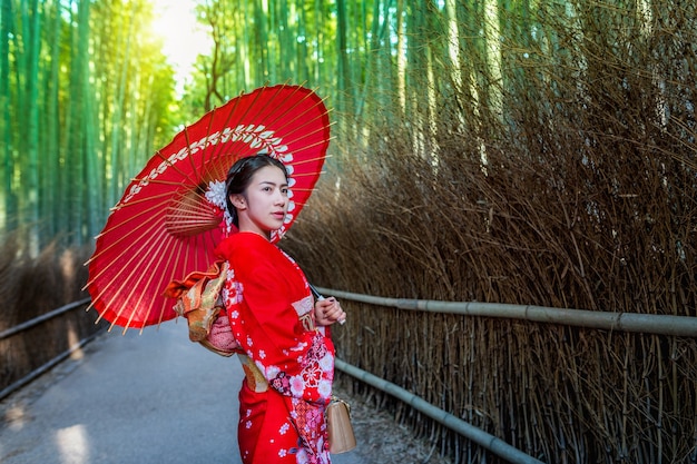 Foto grátis floresta de bambu. mulher asiática vestindo quimono tradicional japonês na floresta de bambu em kyoto, japão.