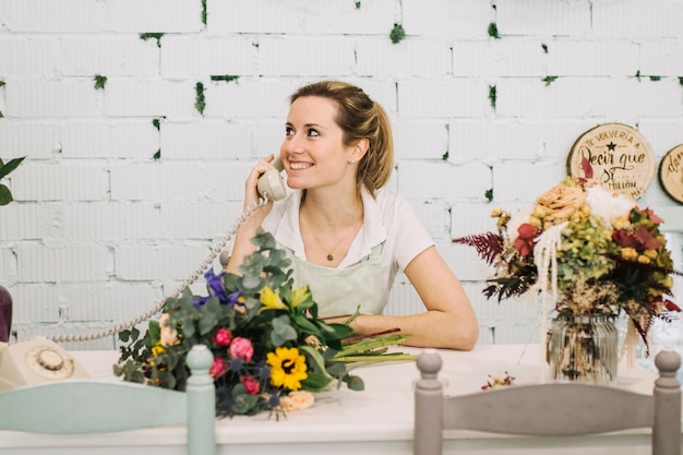 Florista alegre falando no telefone na mesa