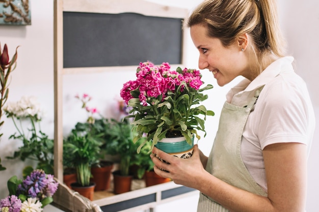 Florista alegre que cheira a flor em vaso