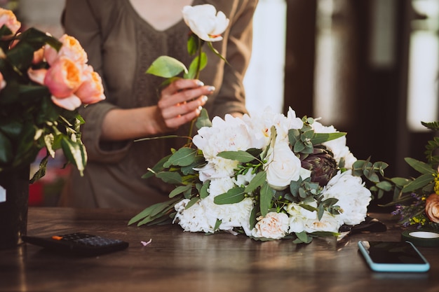 Florista de mulher em sua própria loja floral, cuidando de flores