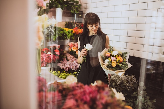 Florista de mulher em sua própria loja floral, cuidando de flores