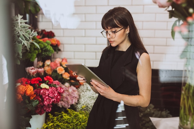 Florista de mulher em sua própria loja floral, cuidando de flores