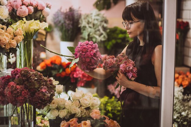 Florista de mulher em sua própria loja floral, cuidando de flores