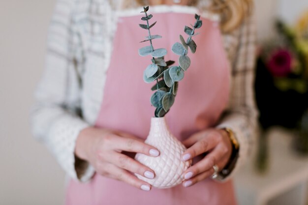 Florista em avental com planta em vaso