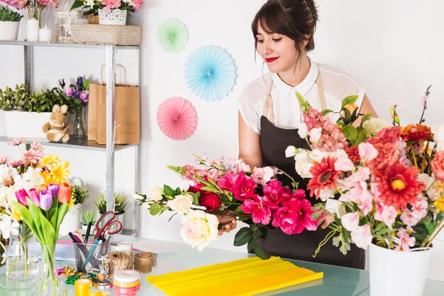 Florista feminina fazendo buquê de flores na loja floral