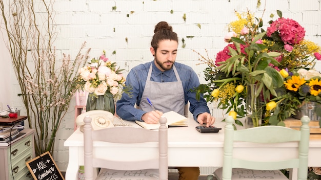 Florista masculina, calculando as finanças na loja de flores