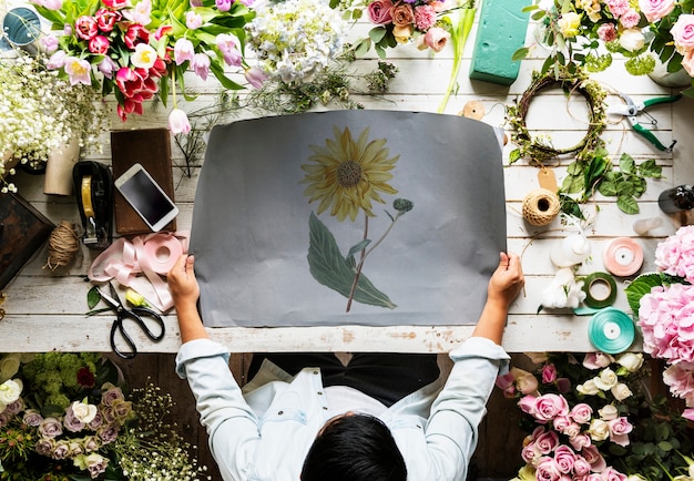 Florista, mostrando o papel de espaço vazio Design na mesa de madeira com flores frescas decorar