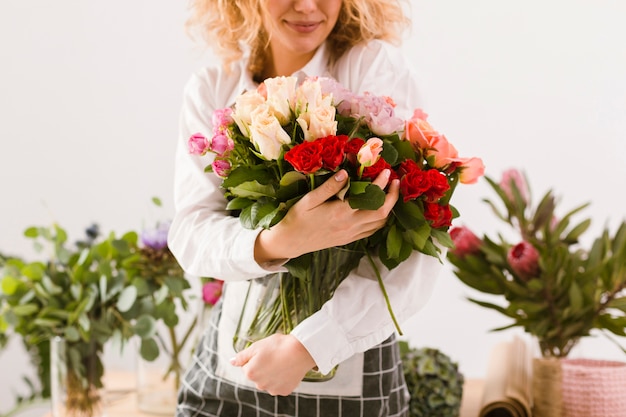 Florista sorridente close-up, segurando o frasco com flores