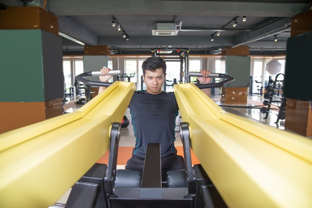 Focada homem asiático treinamento na máquina de exercício