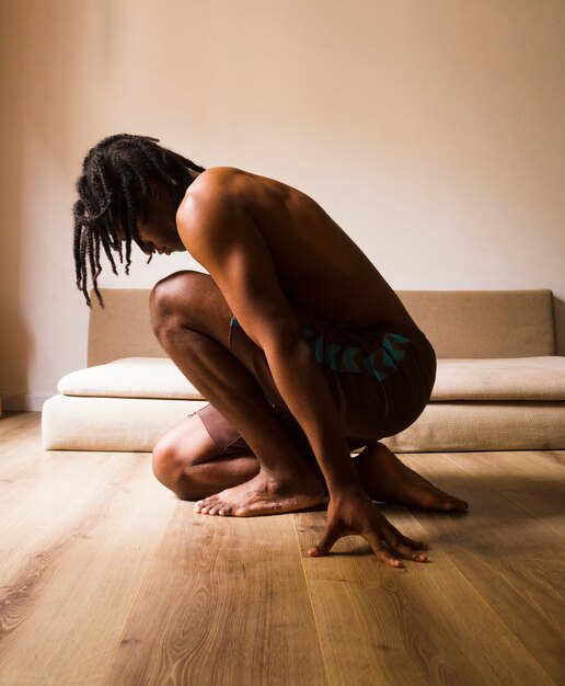 Focada homem sentado de lado e meditando dentro de casa