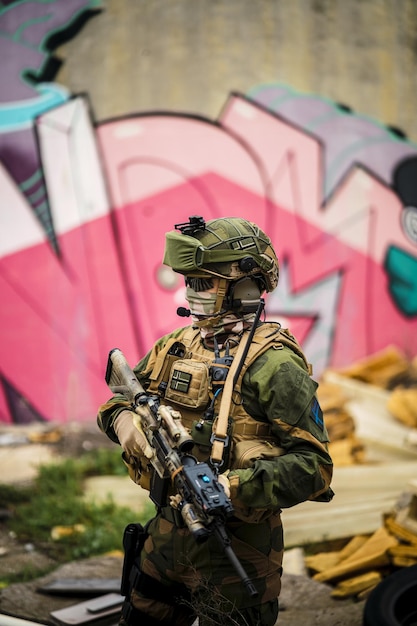 Foco raso de um soldado da força especial em uma camuflagem segurando uma arma em uma área abandonada