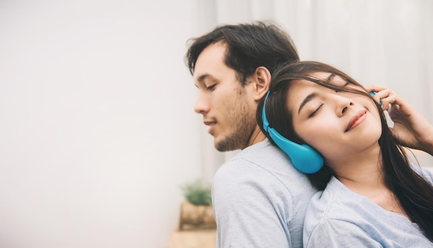 Foco seletivo feliz doce jovem casal relaxando e ouvindo música na cama no quarto momentos românticos