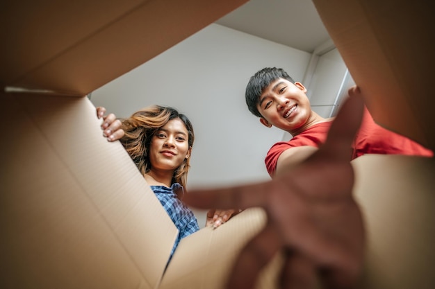 Foco seletivo jovem casal feliz abre o pacote e pega algo da caixa de papelão jovem casal no novo conceito de casa