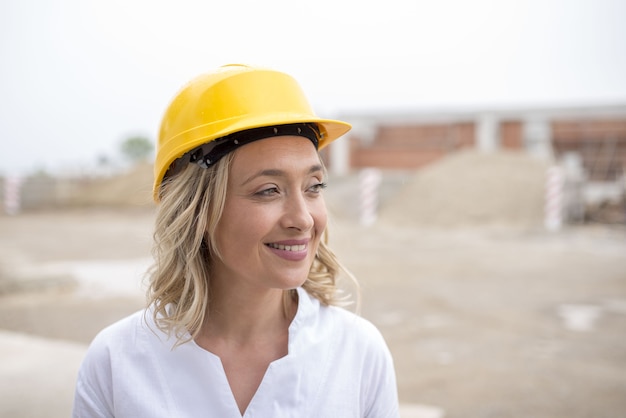 Foco superficial de uma jovem trabalhadora da construção civil com um capacete amarelo durante o dia