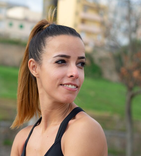 Foco superficial de uma mulher sorridente fazendo exercícios em um parque sob o sol