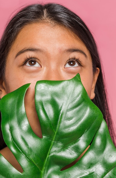 Folha de Monstera cobrindo o rosto de mulher