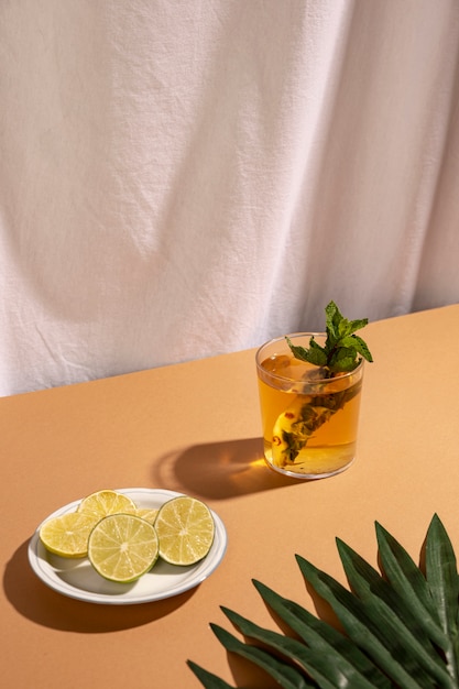 Folha de palmeira com rodelas de limão e bebida cocktail sobre a mesa marrom