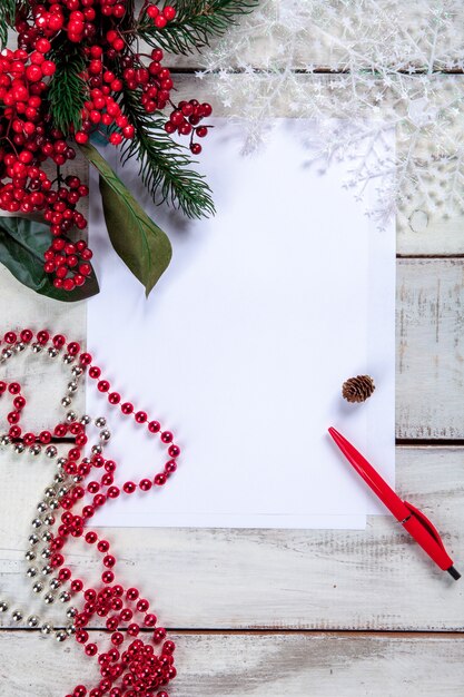 folha de papel em branco na mesa de madeira com uma caneta e decorações de Natal.