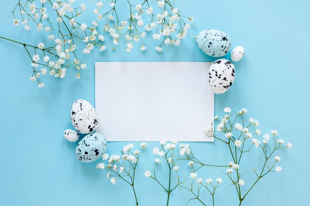 Folha de papel na mesa ao lado de ovos e flores pintados