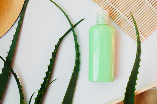 Folhas de aloe vera com um frasco de creme de beleza