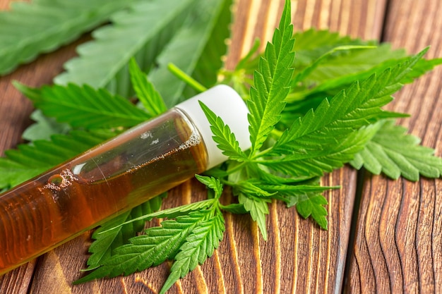 Folhas de cannabis e óleo em fundo de madeira