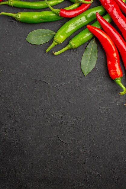 Folhas de louro picantes de pimentão vermelho e verde no topo da mesa preta com espaço livre