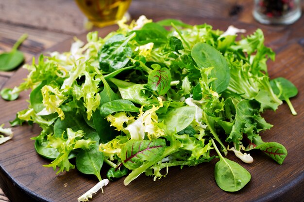 Folhas frescas de salada mista sobre um fundo de madeira.