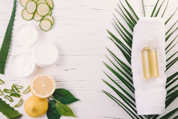 Folhas tropicais de vista superior com ferramentas de beleza e cosméticos