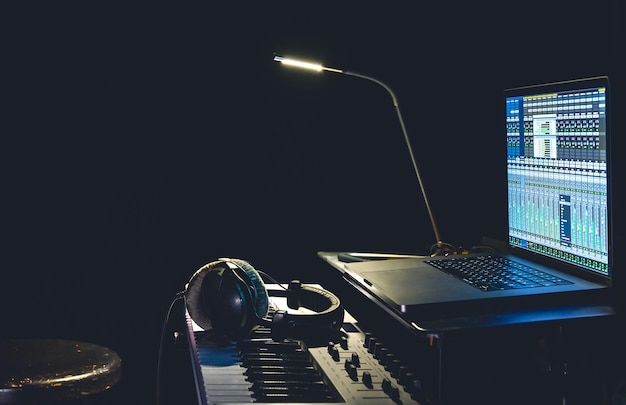Fones de ouvido com teclado MIDI e um laptop com programa para criar música