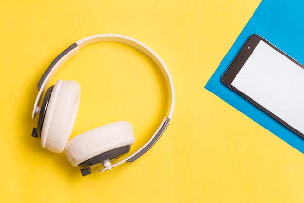 Fones de ouvido e smartphone em fundo colorido