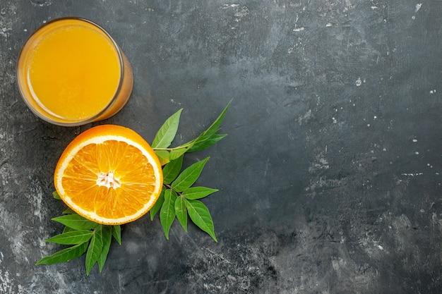 Fonte de vitamina corta laranjas frescas e suco com folhas em fundo cinza