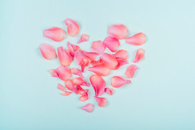 Forma de coração de pétalas de rosas na mesa azul