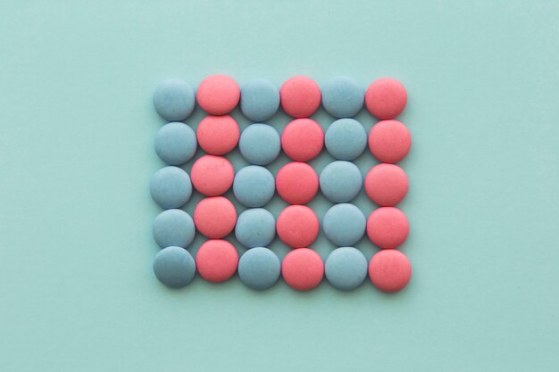Forma retangular feita de doces-de-rosa e azuis na superfície verde