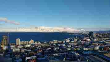 Foto grátis foto aérea da cidade costeira de reykjavik com montanhas cobertas de neve em um céu azul