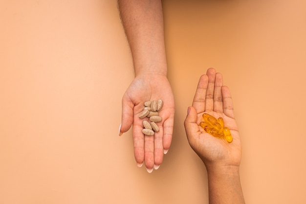 Foto aérea de mãos cheias de drogas em um fundo laranja