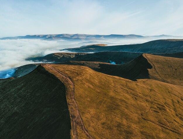 Foto aérea de montanhas cercadas por nuvens brancas