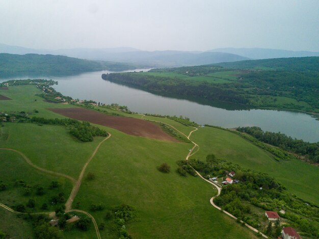 Foto grátis foto aérea de paisagens verdes, campos e um rio sob um céu nublado em um dia ensolarado