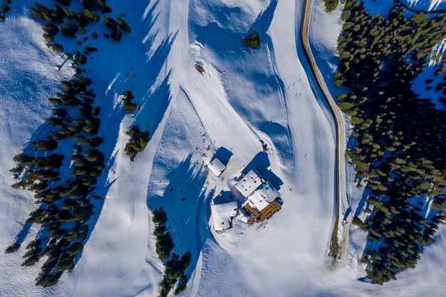 Foto aérea de pequenas casas em uma montanha nevada cercada por árvores durante o dia