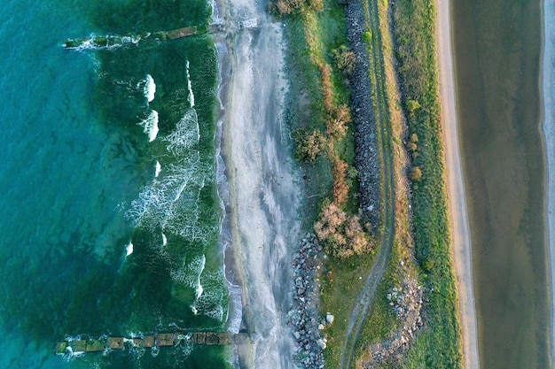 Foto aérea de uma costa estreita no meio do mar com um caminho e vegetação