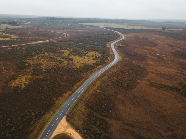 Foto aérea de uma estrada no meio de uma paisagem verde na nova floresta, perto de Brockenhurst, Reino Unido