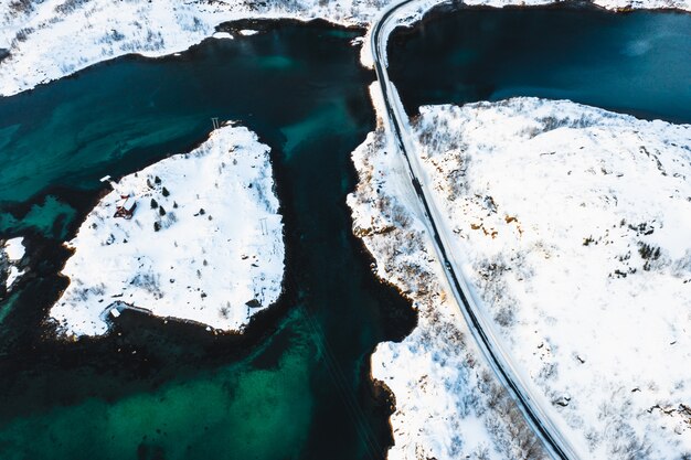 Foto aérea de uma estrada que atravessa ilhas nevadas em um corpo de água
