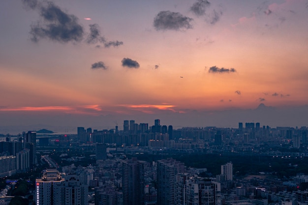 Foto aérea de uma grande cidade sob um céu nublado laranja-azulado ao pôr do sol