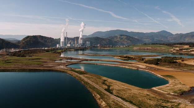 Foto aérea de uma paisagem cercada por montanhas e lagos com desastre industrial